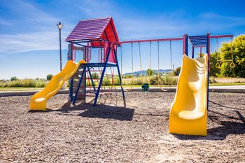 A playground with a yellow slide and a red and blue structure.
